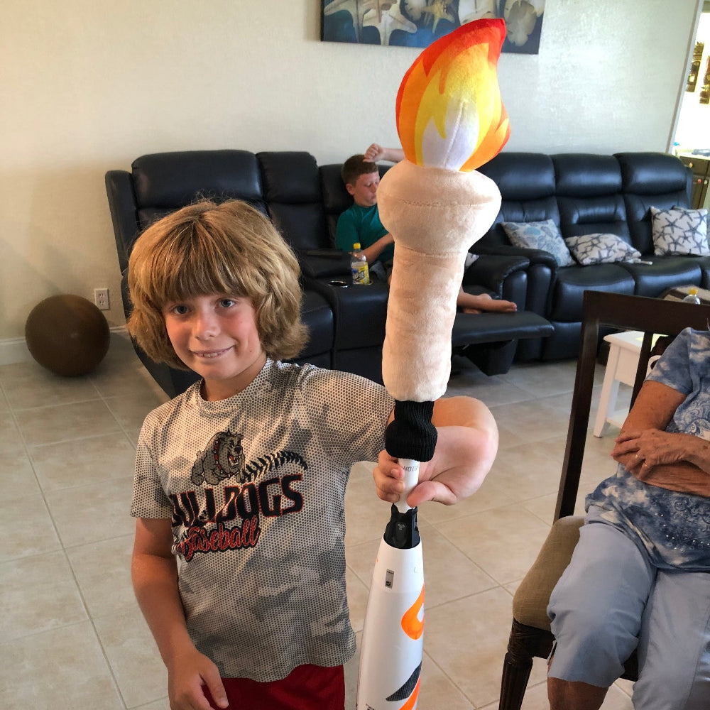 Child holding a toy bat with flame design in a living room setting